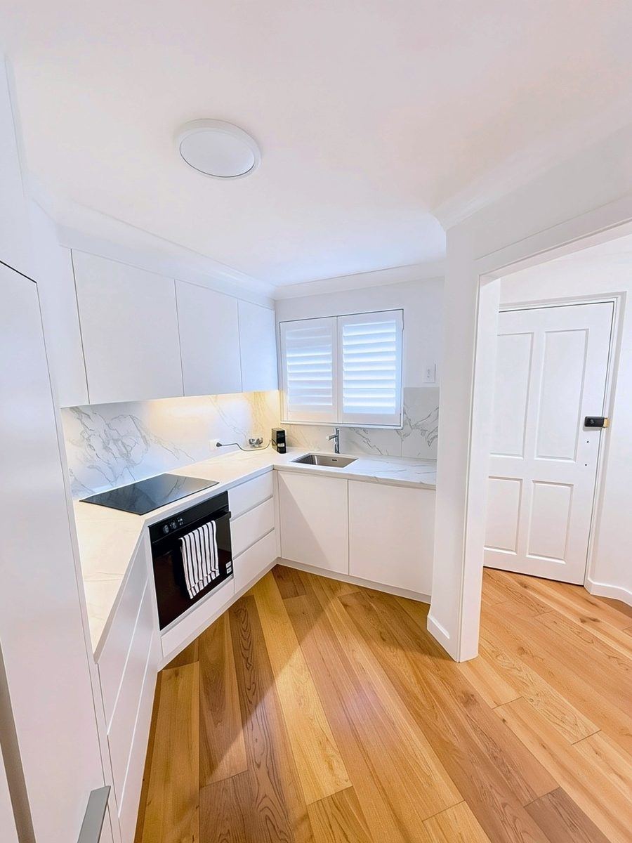 After: the new kitchen, with white cabinetry and marble-look benchtops