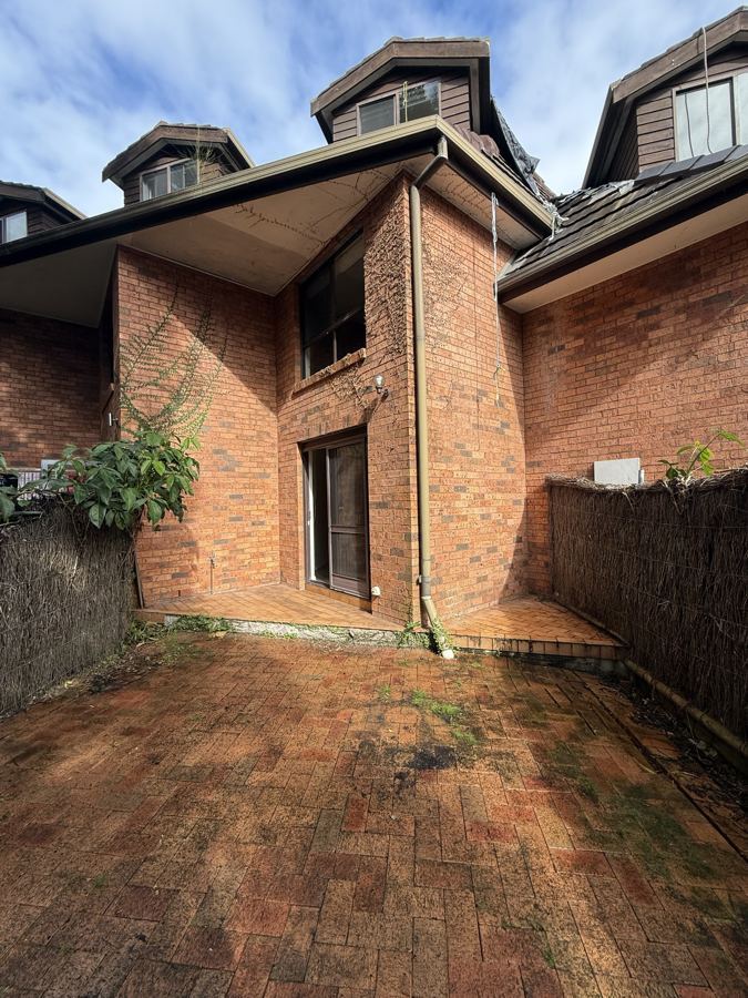 Before: the back of the townhouse, with worn brick paving and overgrown courtyard
