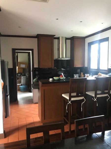 Before: the kitchen, with dark timber cabinetry and terracotta floor tiles
